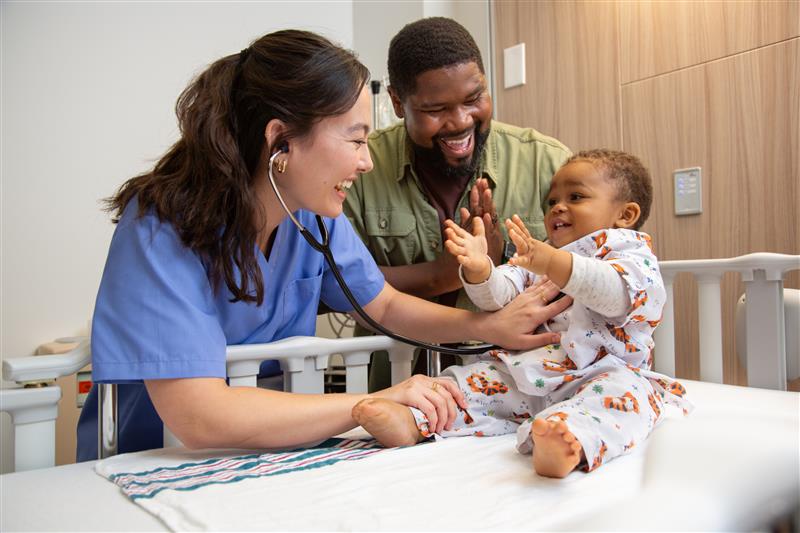 Nurse checking on a baby with patient dad smiling