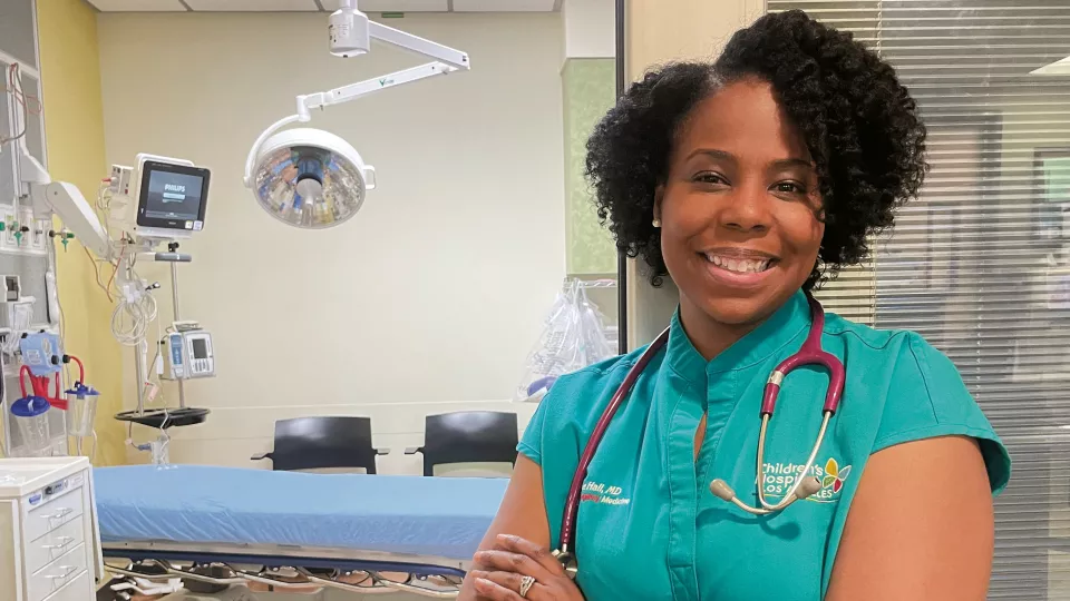 Jeanine Hall, MD, MPH stands with arms crossed in front of hospital room