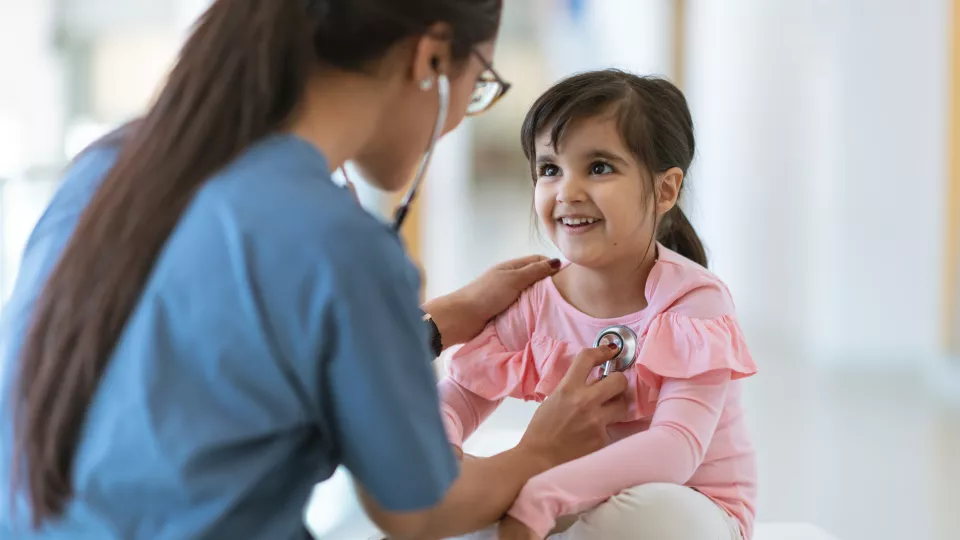 Nurse checks heart beat of young girl