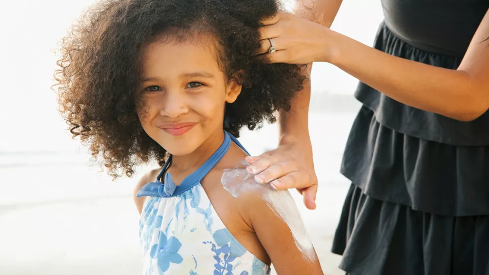 Mom putting sunscreen on a girl