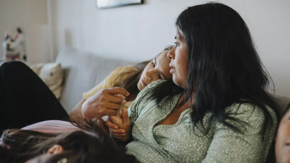 Mother comforting two children on couch