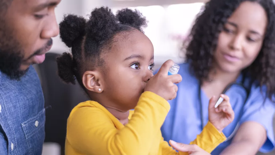Young girl learning how to use asthma inhaler